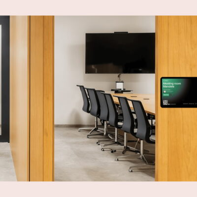 Modern meeting room with a wall-mounted room booking display showing availability for “Meeting room Mandela.”