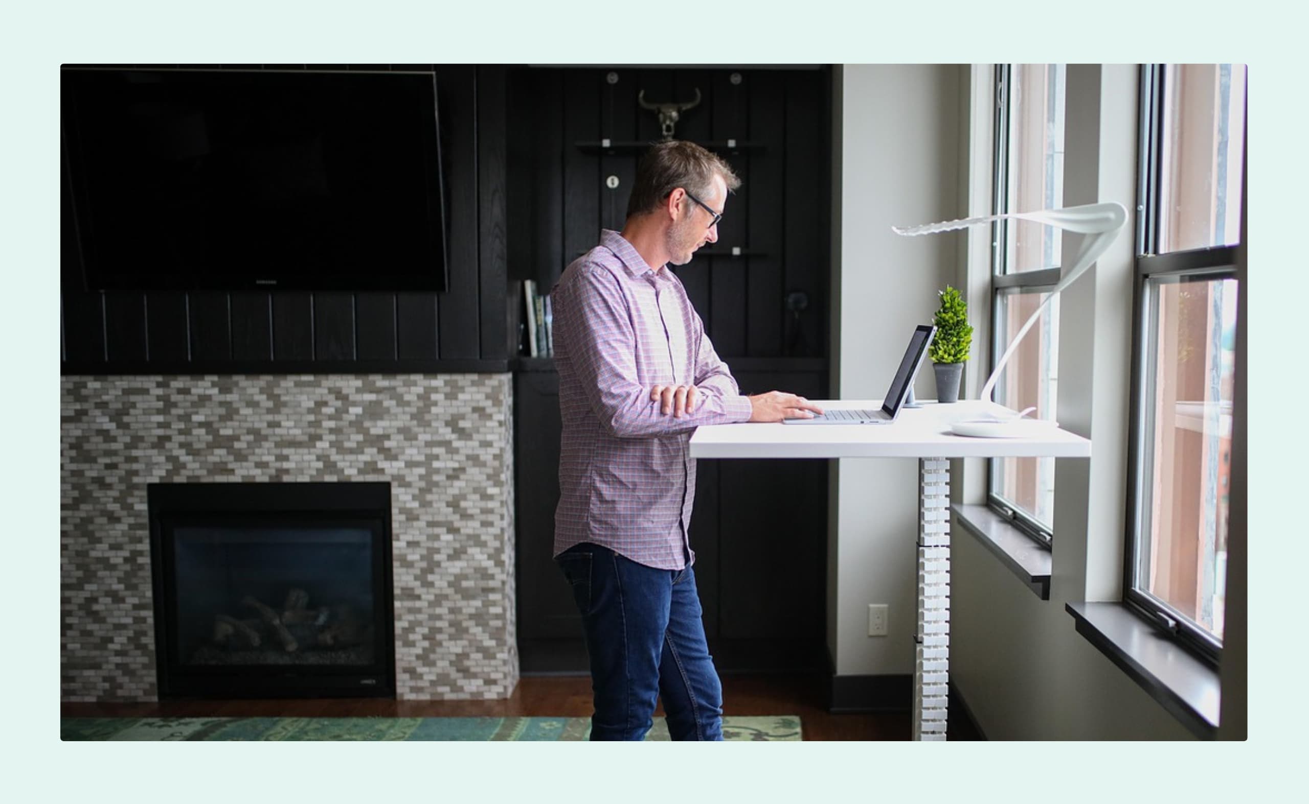 A man working at a laptop in a modern, open office space with other people in the background.