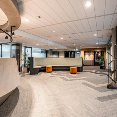 Modern office lobby with curved seating, soft lighting, and a clean, open layout.